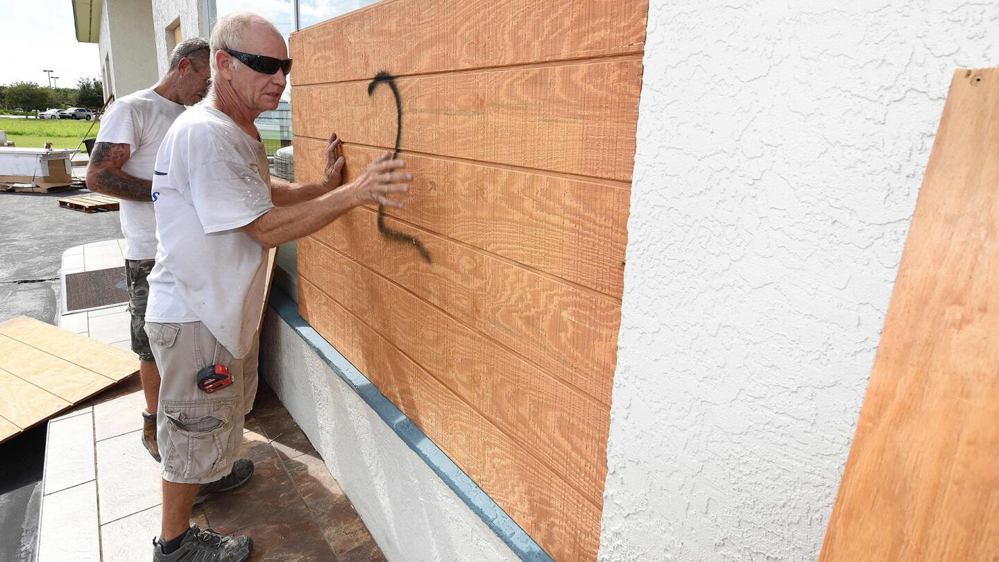 Anthony Schirado (L) and Tom Kennedy (R) put up plywood to cover the windows of store front ahead of Hurricane Matthew on Cocoa Beach, Florida on October 5, 2016.