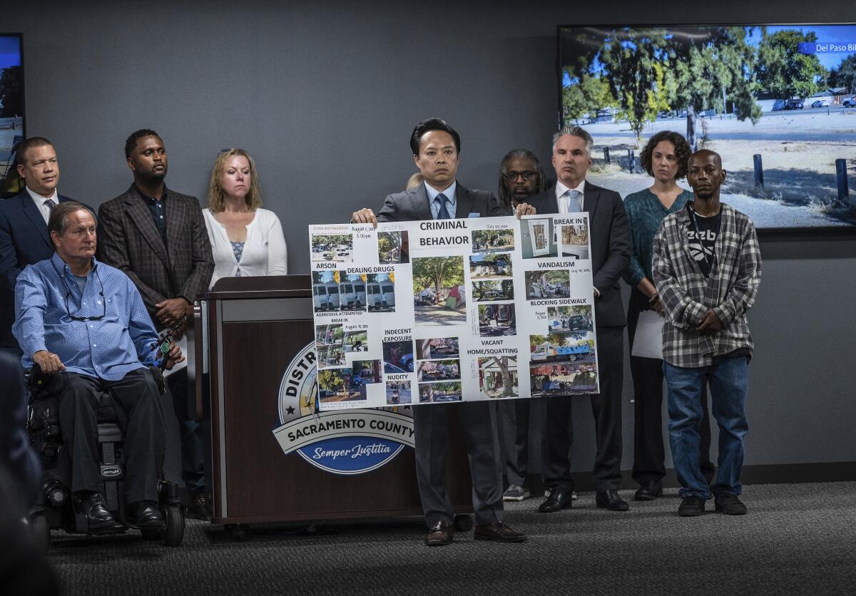 Sacramento County district attorney holds a poster collage with the words 'criminal behavior.'