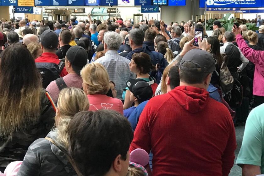 People wait to get through security at the Orlando International Airport following a security incident on Saturday, Feb. 2, 2019. Passengers on shuttles to gates at Florida's busiest airport had to be brought back for a second screening, bringing security checkpoints to a temporary standstill. A spokeswoman for Orlando International Airport told television station WKMG on Saturday that the passengers were returned in "an abundance of caution" after some passengers may have gotten through the checkpoints without being screened property. (Jonathan Hayward/The Canadian Press via AP)