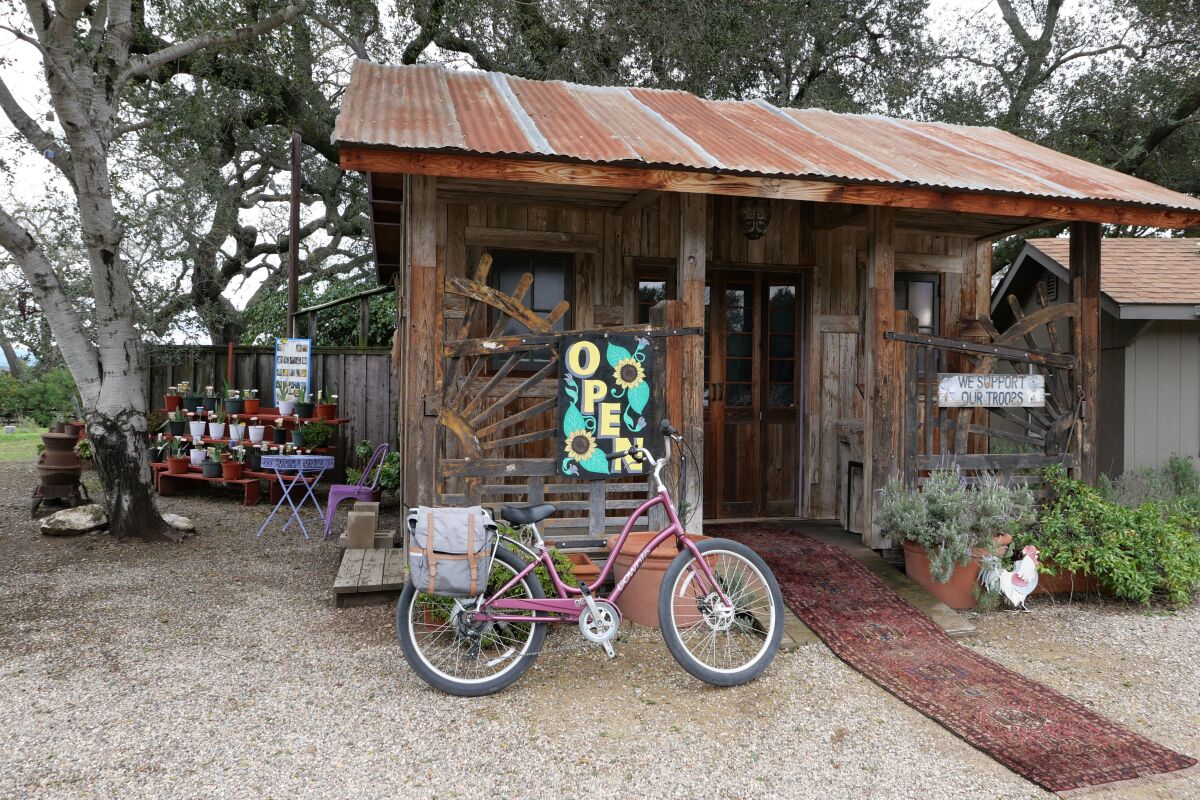 A bike leans up against a small wooden building with an "open" sign. 