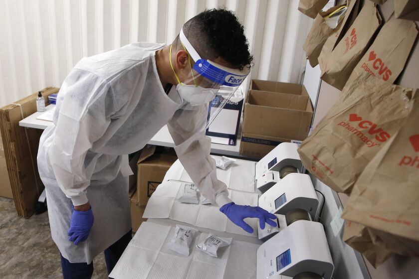 Berto Cortez, a CVS pharmacy technician, shows how COVID-19 tests are processed in a testing area set up by CVS at St. Vincent de Paul medical clinic, Monday, June 15, 2020, in Phoenix. The Arizona Department of Health Services posted on its website Monday another 1,104 cases of COVID-19 and eight additional deaths, bringing the statewide total number of coronavirus cases to 36,705 and related deaths to 1,194. (AP Photo/Ross D. Franklin)
