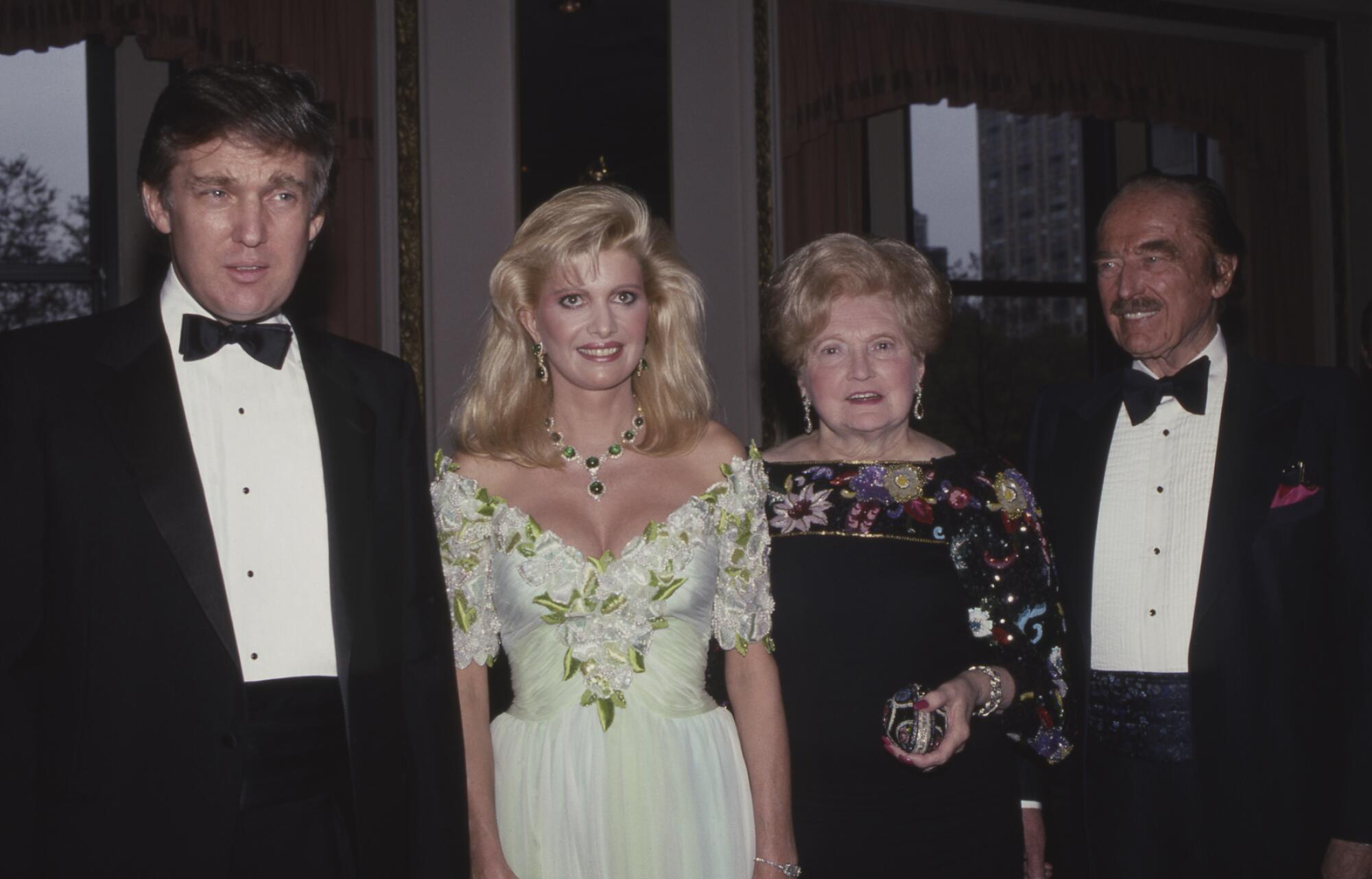 Two women, one in a cream evening dress and the other in a black one, are flanked by men in dark suits and bow ties.