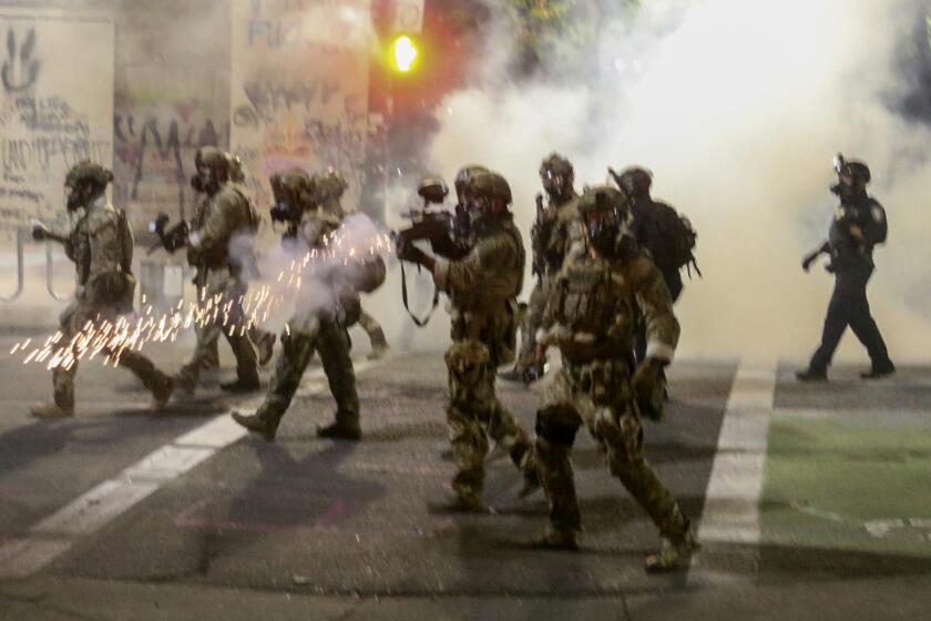 Police respond to protesters during a demonstration, Friday, July 17, 2020 in Portland, Ore. Militarized federal agents deployed by the president to Portland, Oregon, fired tear gas against protesters again overnight as the city’s mayor demanded that the agents be removed and as the state’s attorney general vowed to seek a restraining order against them. (Dave Killen/The Oregonian via AP)