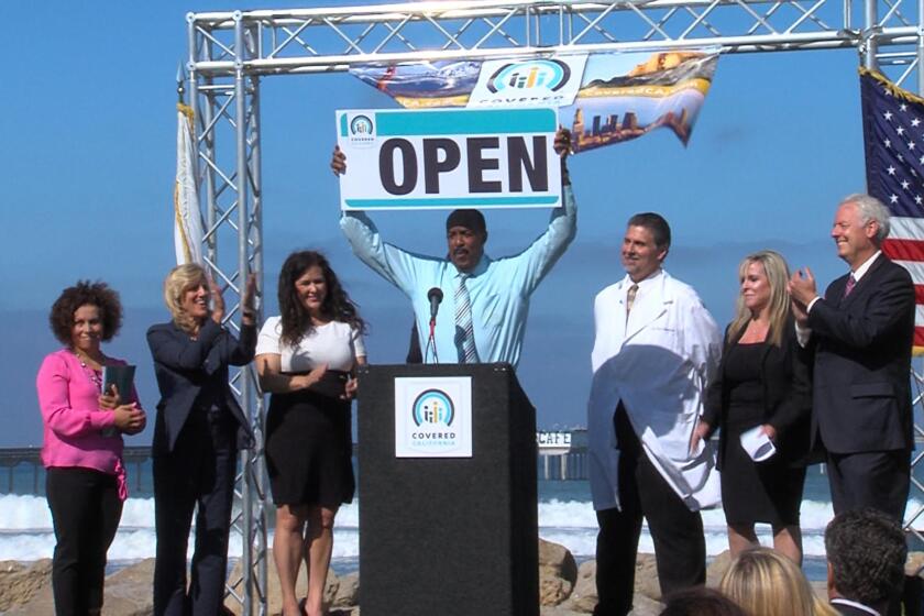 In 2013, Covered California board member Robert Ross, center, declares the start of the exchange's first open-enrollment period.