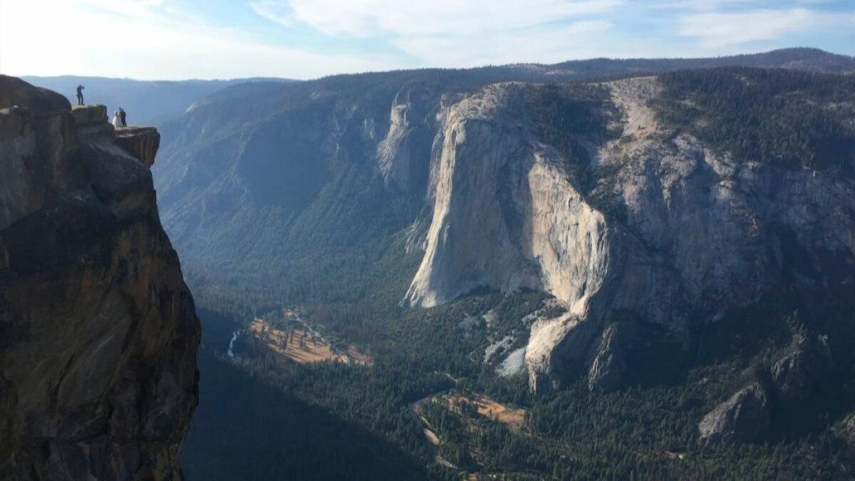 A wedding couple is seen being photographed at Taft Point in Yosemite National Park.