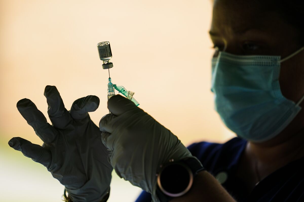 A person prepares a syringe placed into a vial.
