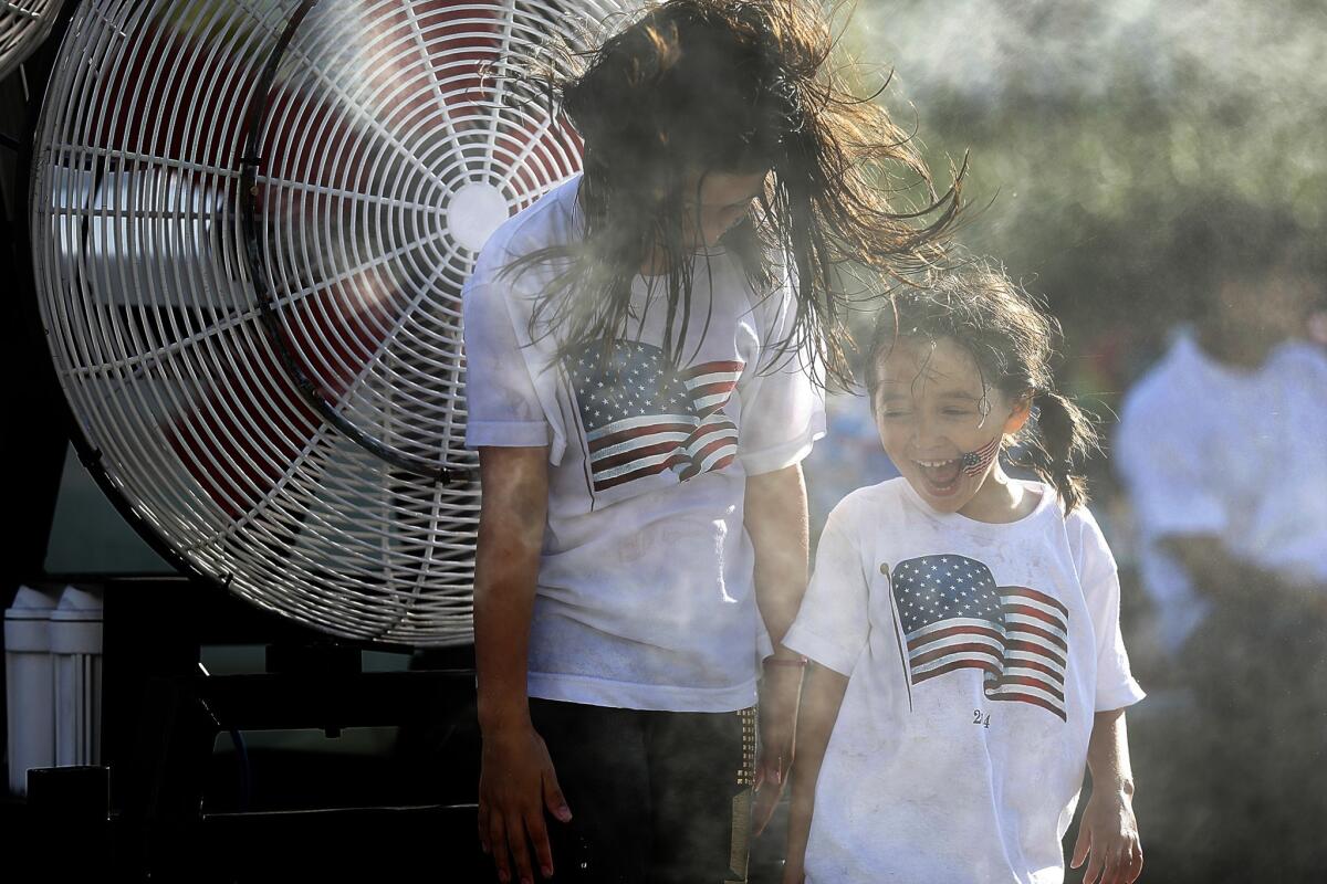 Sisters Cherokee, 7, and Maya Lynne Spears, 4 of Los Angeles enjoy a misting station as they join thousands of people at the Grand Park Fourth of July Block Party in downtown Los Angeles.