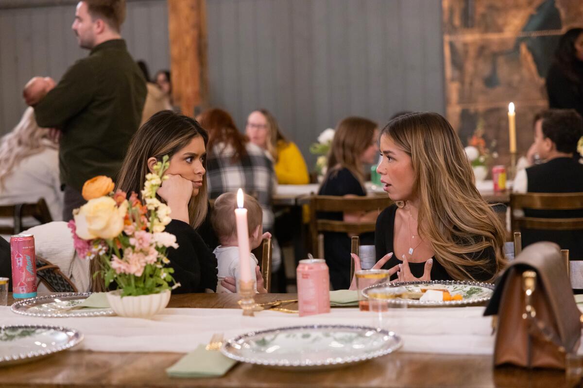 Two women sit next to each other at a dinner.