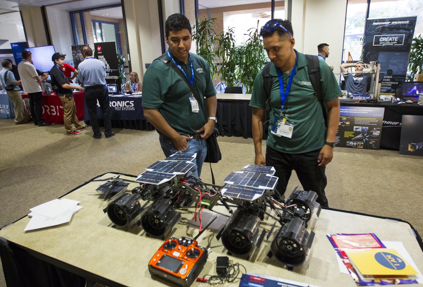 Alfredo Herrera and Jairo Sanchez from Cal Poly Pomona look at a miniature replica of the Mars Rover during an Aerospace Symposium and Expo at UC Irvine on Thursday.