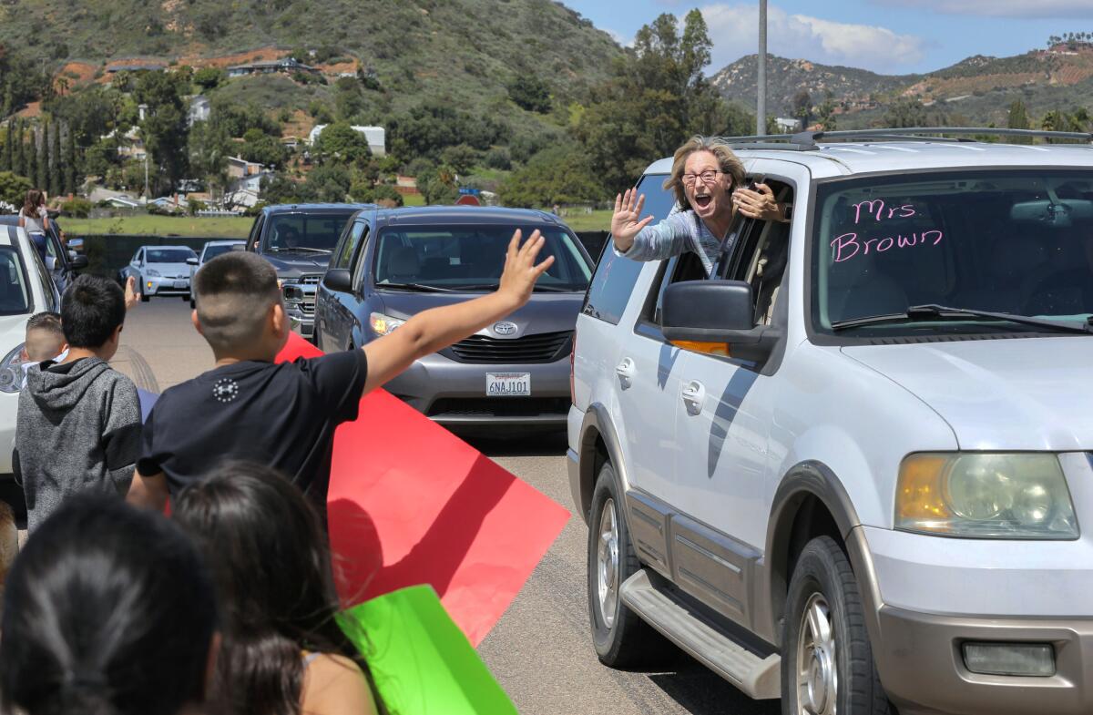 Reidy Creek Elementary School first grade teacher Desiree Brown greets students as her teacher caravan from the school passes by students and parents parked along Conway Drive, near North Avenue on Friday, March 27.
