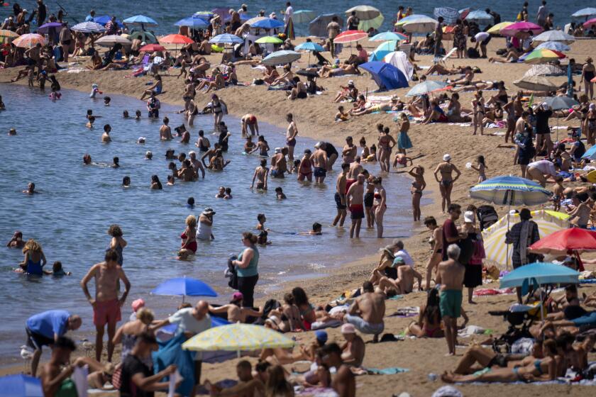 Bañistas se refrescan en el agua mientras otros toman el sol en una playa de Barcelona, España, el miércoles 24 de julio de 2024. Varias regiones de España estaban en alerta por altas temperaturas. (AP Foto/Emilio Morenatti)