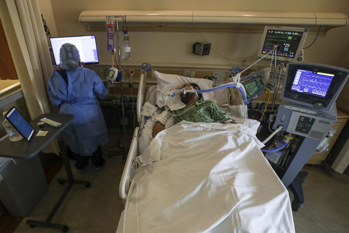 A patient on a ventilator lies in a hospital bed.