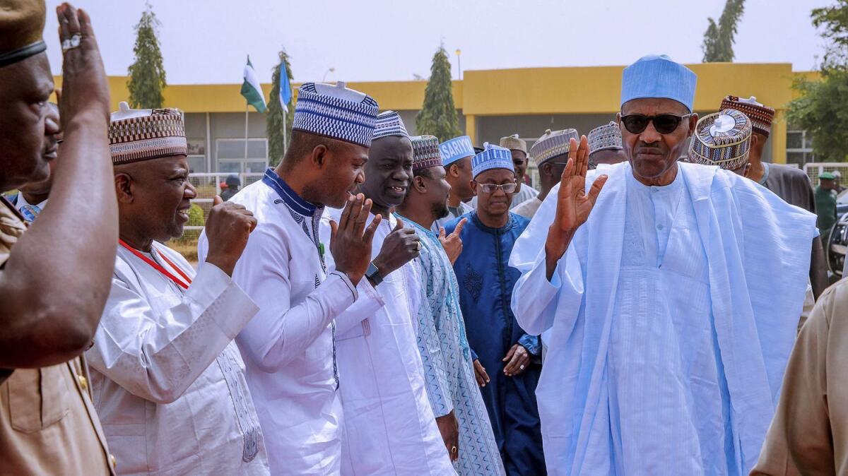 Nigerian President Muhammadu Buhari, right, greets supporters in Daura as he leaves for the capital, Abuja, on Saturday after the presidential election was postponed.