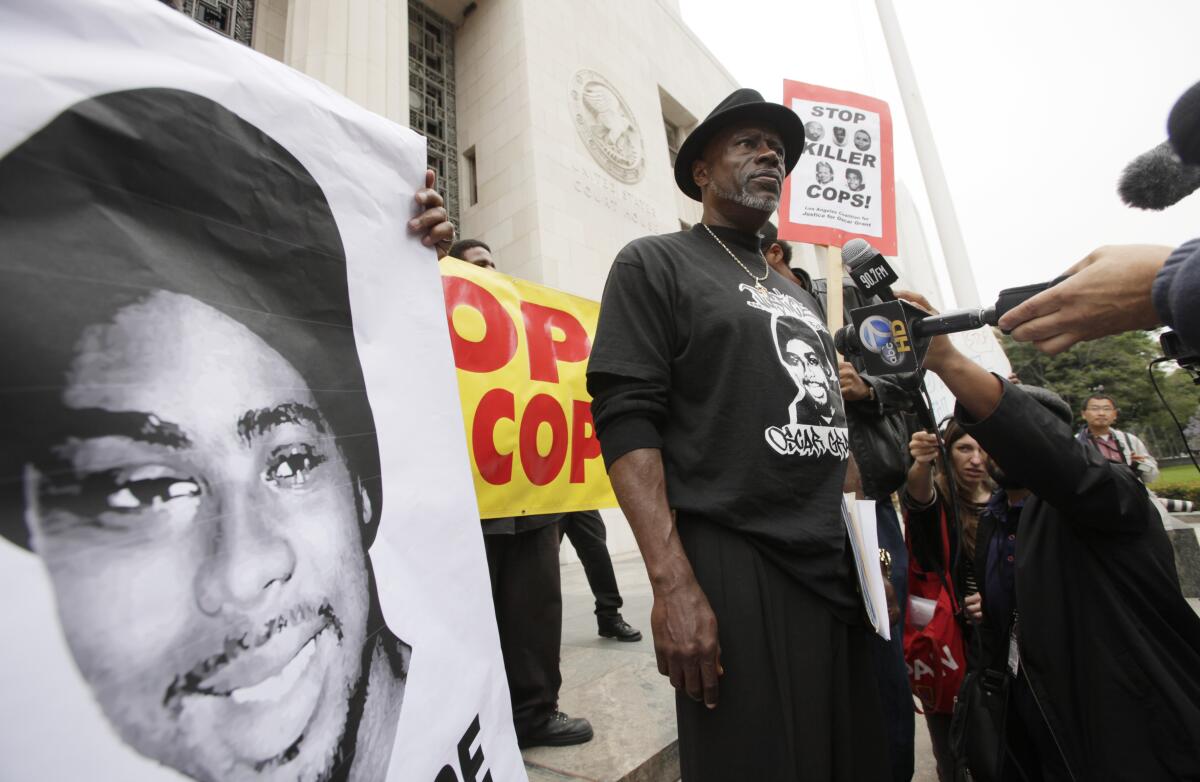 Cephus Johnson stands next to a poster of his nephew Oscar Grant during a protest outside a Los Angeles courthouse in 2011.