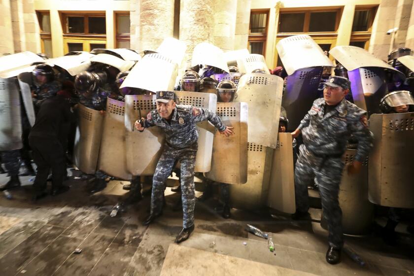 Police officers try to block an entrance of the government building during a protest against Prime Minister Nikol Pashinyan in Yerevan, Armenia, on Wednesday, Sept. 20, 2023. Protesters gathered in central Yerevan, the capital of Armenia, blocking streets and demanding that authorities defend Armenians in Nagorno-Karabakh. (Vahram Baghdasaryan/Photolure via AP)