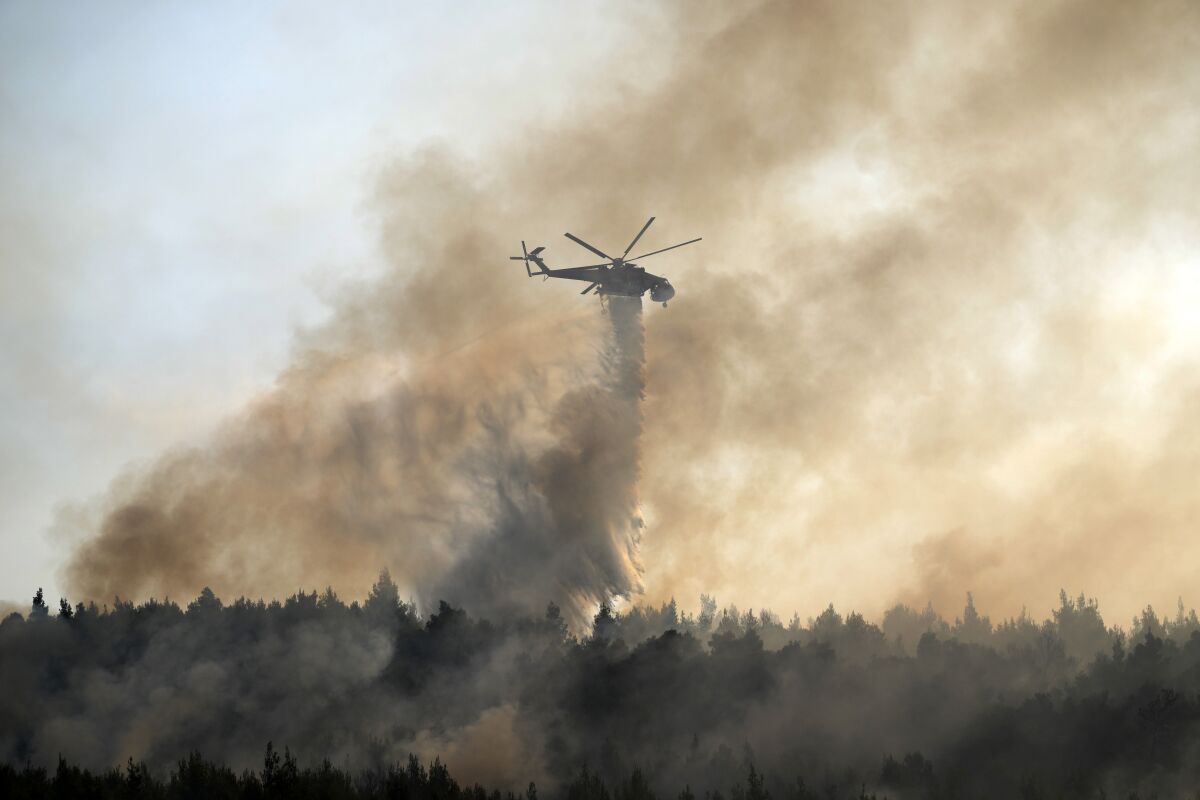 Helicopter dropping water over a fire in Greece