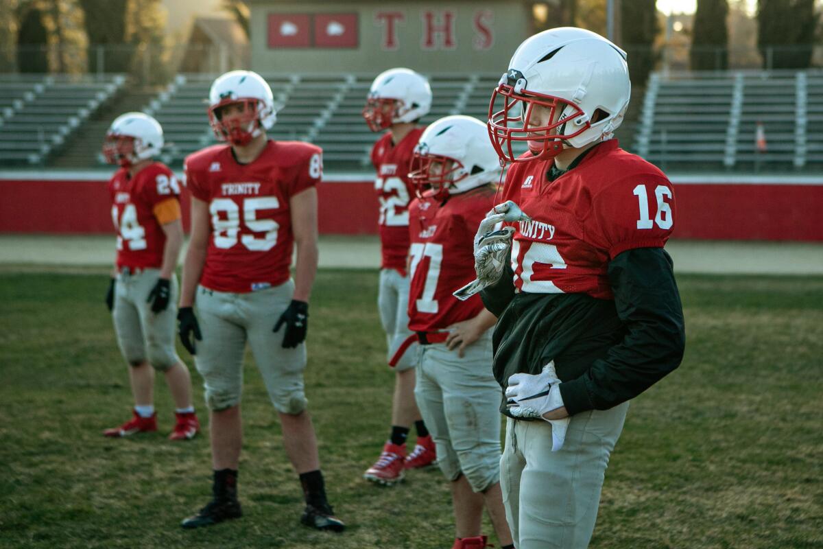 Five uniformed members of the Trinity High School football team stand at a practice last month