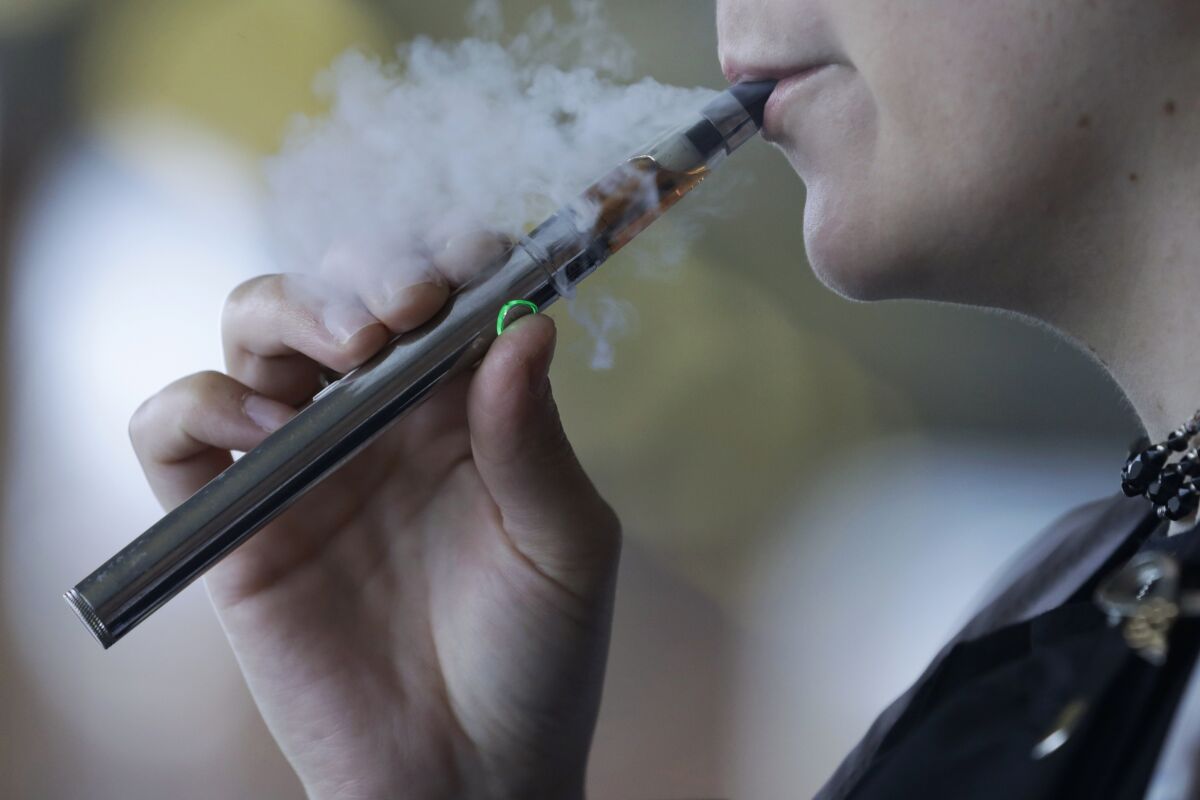 In this file photo, a woman using an electronic cigarette exhales.  