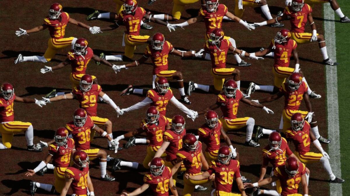 Members of the USC football team clasp hands during a warm up before a game against Utah State on Sept. 10.