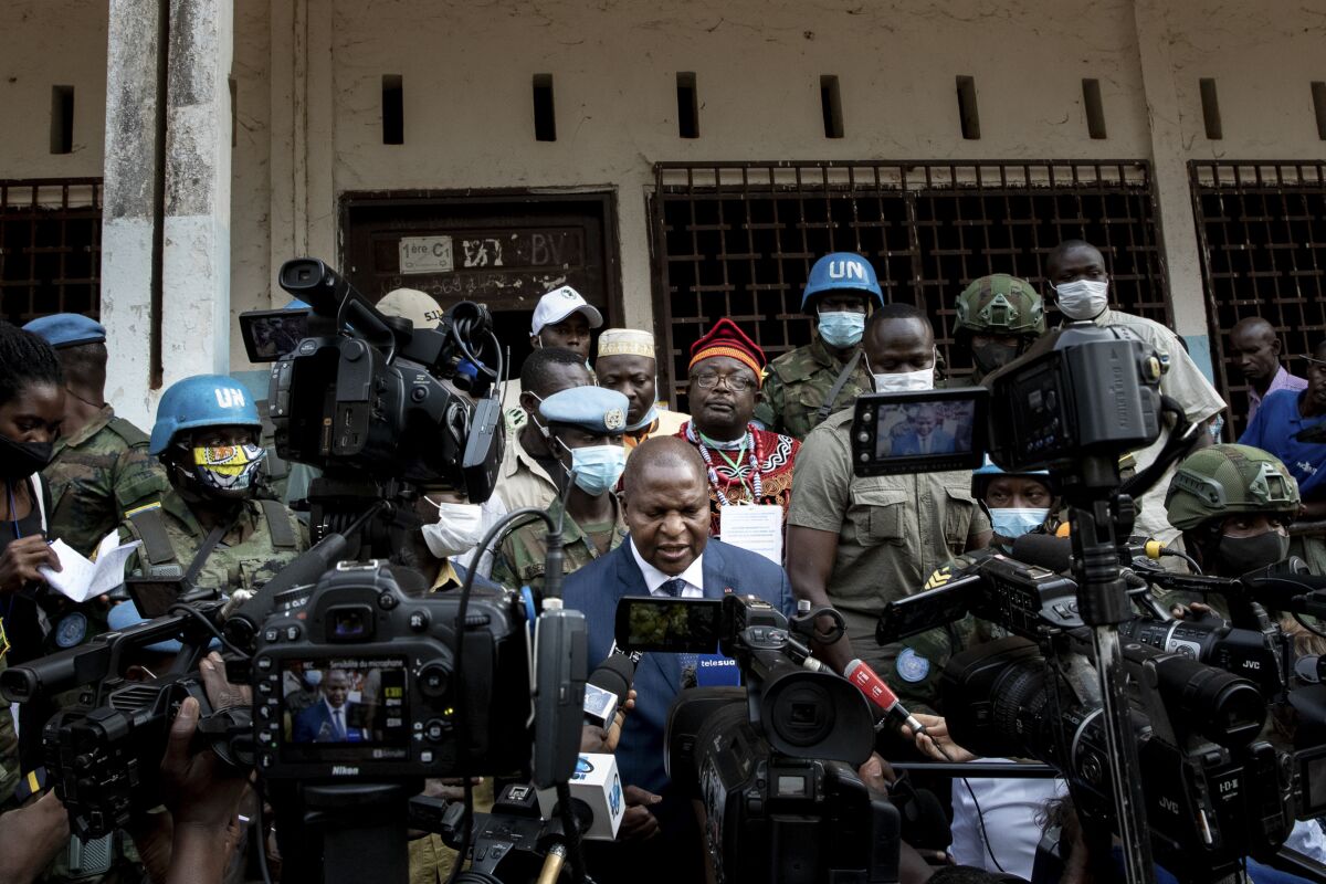 Faustin-Archange Touadera, with military and U.N. peacekeepers, speaks to media holding cameras and microphones.