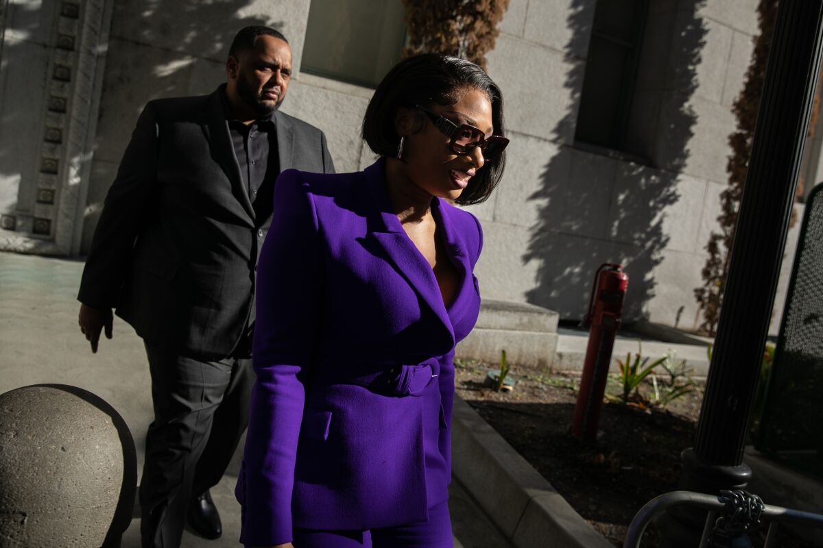 A woman in a purple suit walks in front of a building