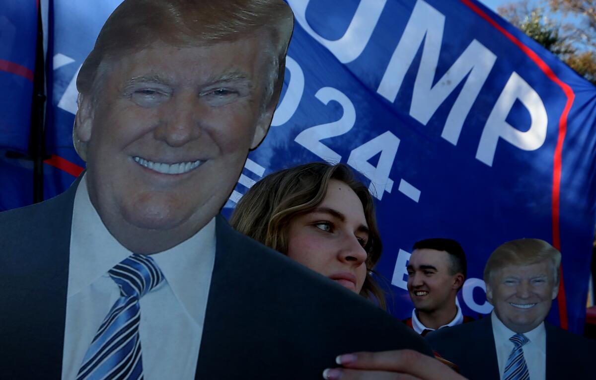 People stand near a large likeness of Donald Trump 