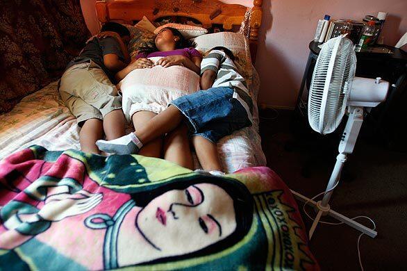 Exhausted from the heat, the Garcia siblings -- Adrian, 10; Wuendi, 15; and Martin, 7 -- nap in their bedroom in Escondido. Their parents sublet the second bedroom of the apartment to help make ends meet.