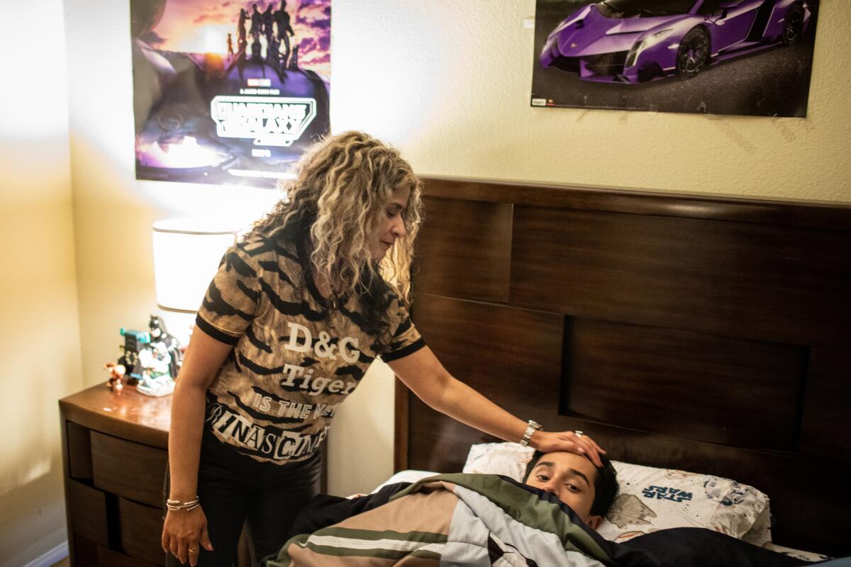 Laguna Niguel, California - May 23: Shashi Singh says goodnight to her son Anirudh,12, at home in Laguna Niguel, CA, Tuesday, May 23, 2023. Singh has been raising her son and daughter Elena,22, alone for over three years, only able to see her husband via Facetime every day. Dr. Pradyuman Singh has been separated from his family since leaving the country in March 2020 to help his mother in India. Singh, currently staying at a hotel in Tijuana, Mexico, is only able to be visited by his son, Anirudh, 12, the sole U.S. citizen in the family. (Jay L. Clendenin / Los Angeles Times)