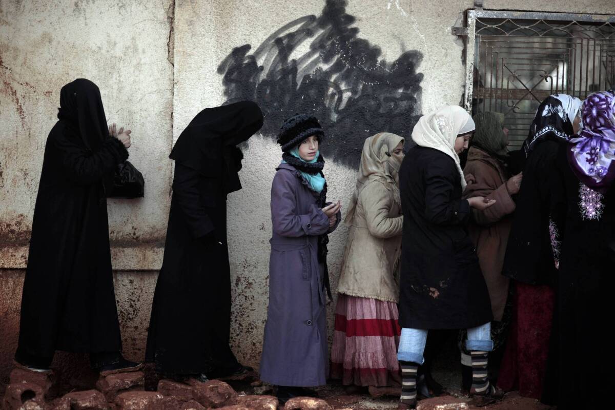 Syrian women wait outside a bakery to buy bread in Maarat Misrin, near Idlib. Elsewhere in Syria, several bomb blasts were reported Wednesday in Damascus, the capital.