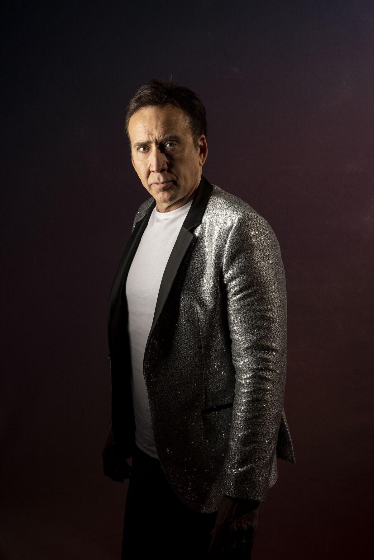 A portrait of a man in a silver suit jacket.