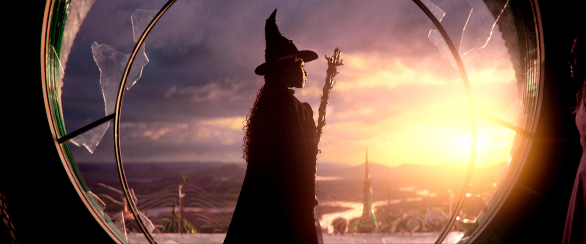 Cynthia Erivo as Elphaba stands in a broken circular window looking out over Oz in "Wicked."