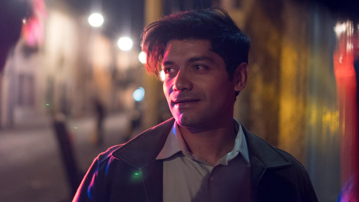 A young man on the street at night with colorful reflections.