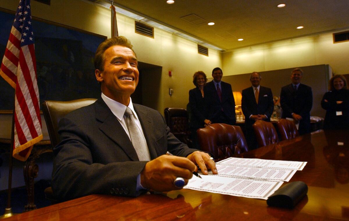 Gov. Arnold Schwarzenegger signs an executive order lowering the car tax shortly after being sworn into office in 2003.