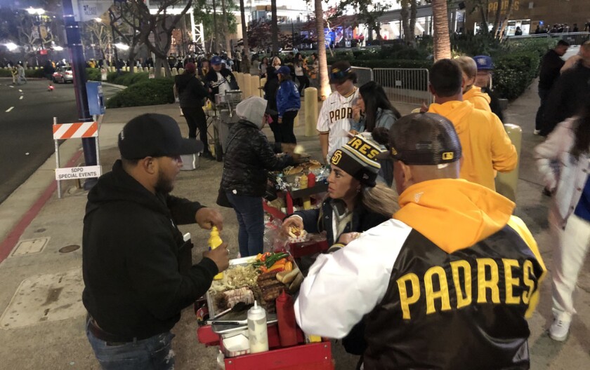 Pedagang kaki lima melakukan bisnis cepat menjual hot dog setelah pertandingan Jumat malam.