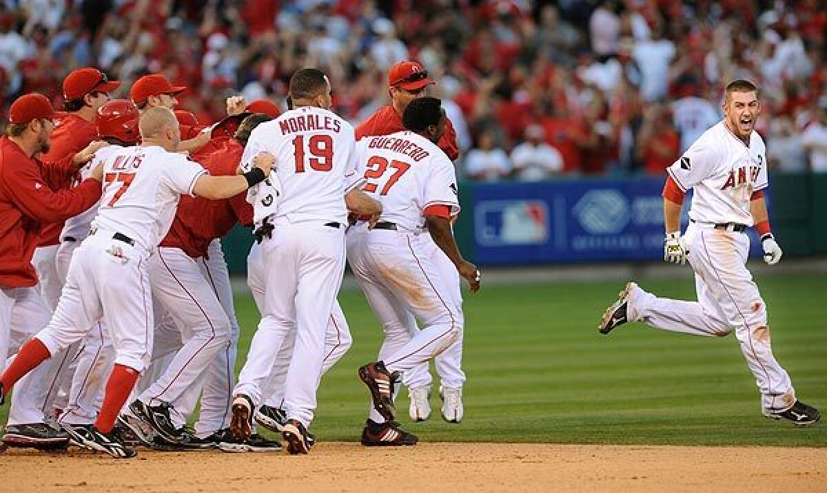 Angels catcher Jeff Mathis, right, is chased down by teammates after connecting on the game-winning hit against the Yankees in the 11th inning Monday against the Yankees in Game 3 of the American League Championship Series.