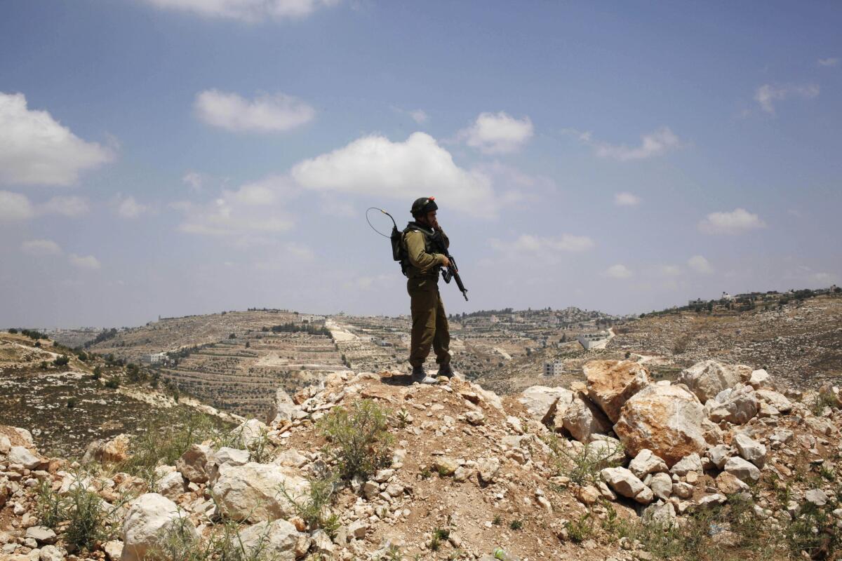 An Israeli soldier stands near the West Bank city of Hebron, as the military searched for three missing Israeli teens.