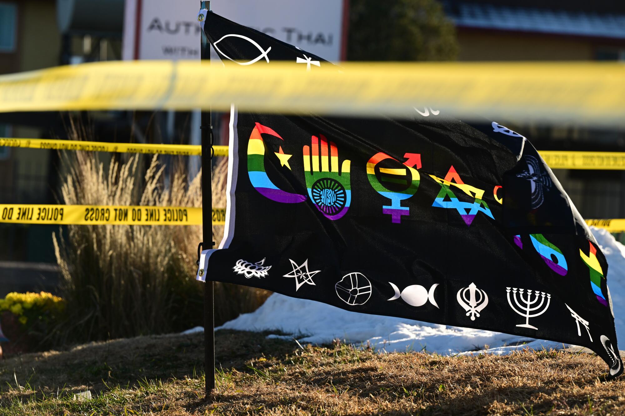 Flags appear near yellow police tape at a makeshift memorial near Club Q in Colorado Springs, Colo.