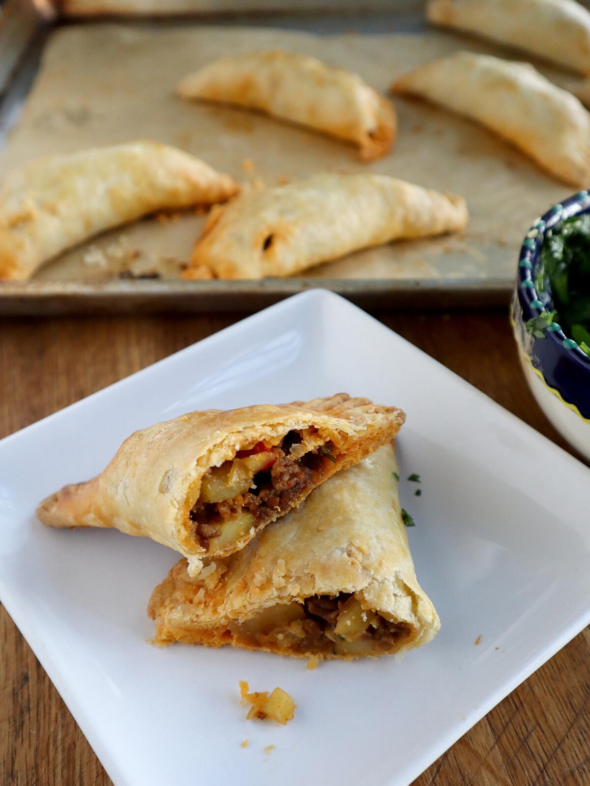 A savory handpie stuffed with Mexican chorizo and potato is presented on a plate, cut in half.