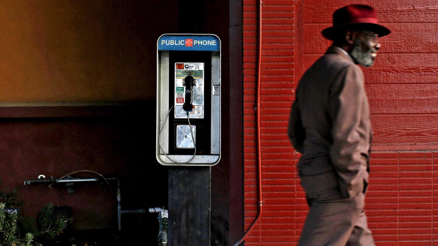 A man walks past a pay phone on South Leimert Boulevard in Los Angeles. Of California's 27,000 pay phones, most are concentrated in L.A. County, the San Francisco Bay Area and along the Interstate 5 corridor, according to the Public Utilities Commission.