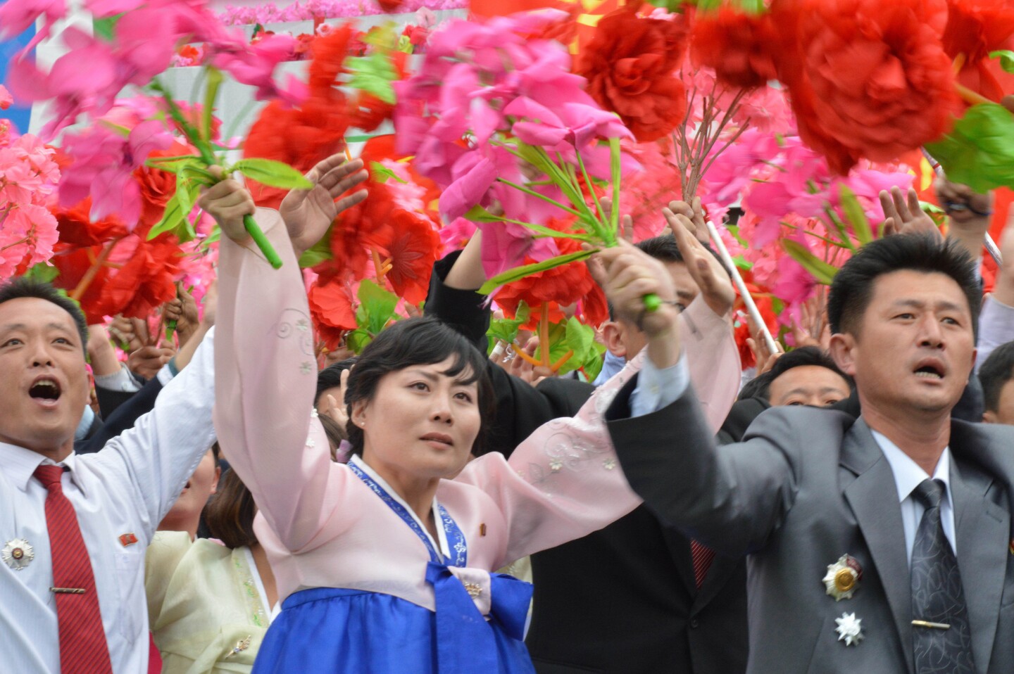 North Korean parade participants wave decorative bouquets of flowers and carry their country's national flag as they march at Kim Il Sung Square in Pyongyang, North Korea.
