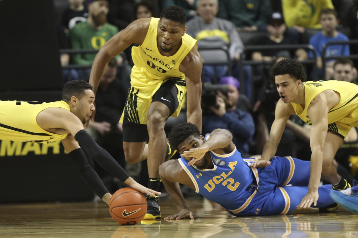 UCLA's Cody Riley battles with Oregon's Anthony Mathis, left, and Francis Okoro, for a loose ball during the first half of a game Jan. 26.