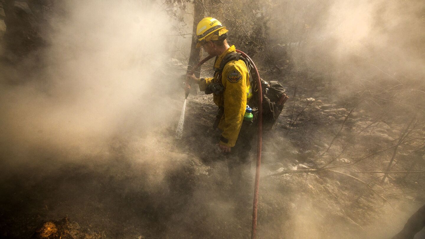 Orange County firefighter Jean Davancens works to put out embers in heavy mulch in El Capitan Canyon while working the Sherpa fire on June 17, 2016.