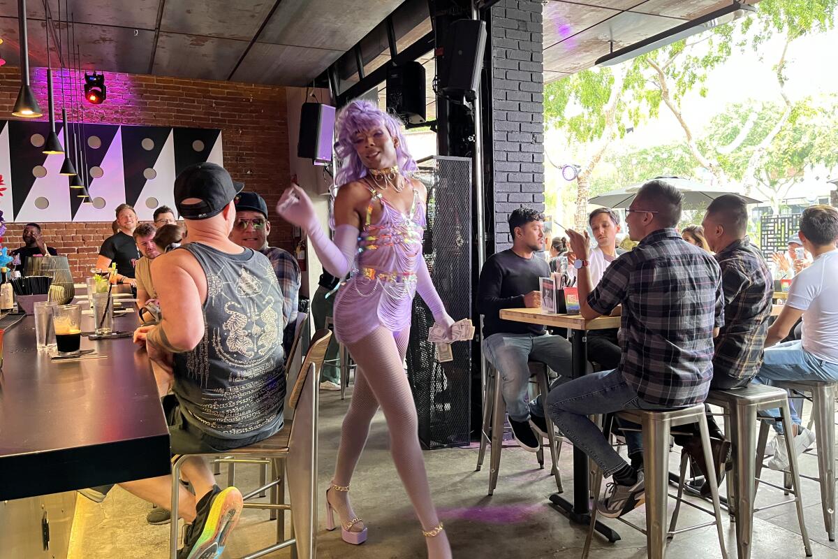A drag queen struts between two tables of fans at Stache.
