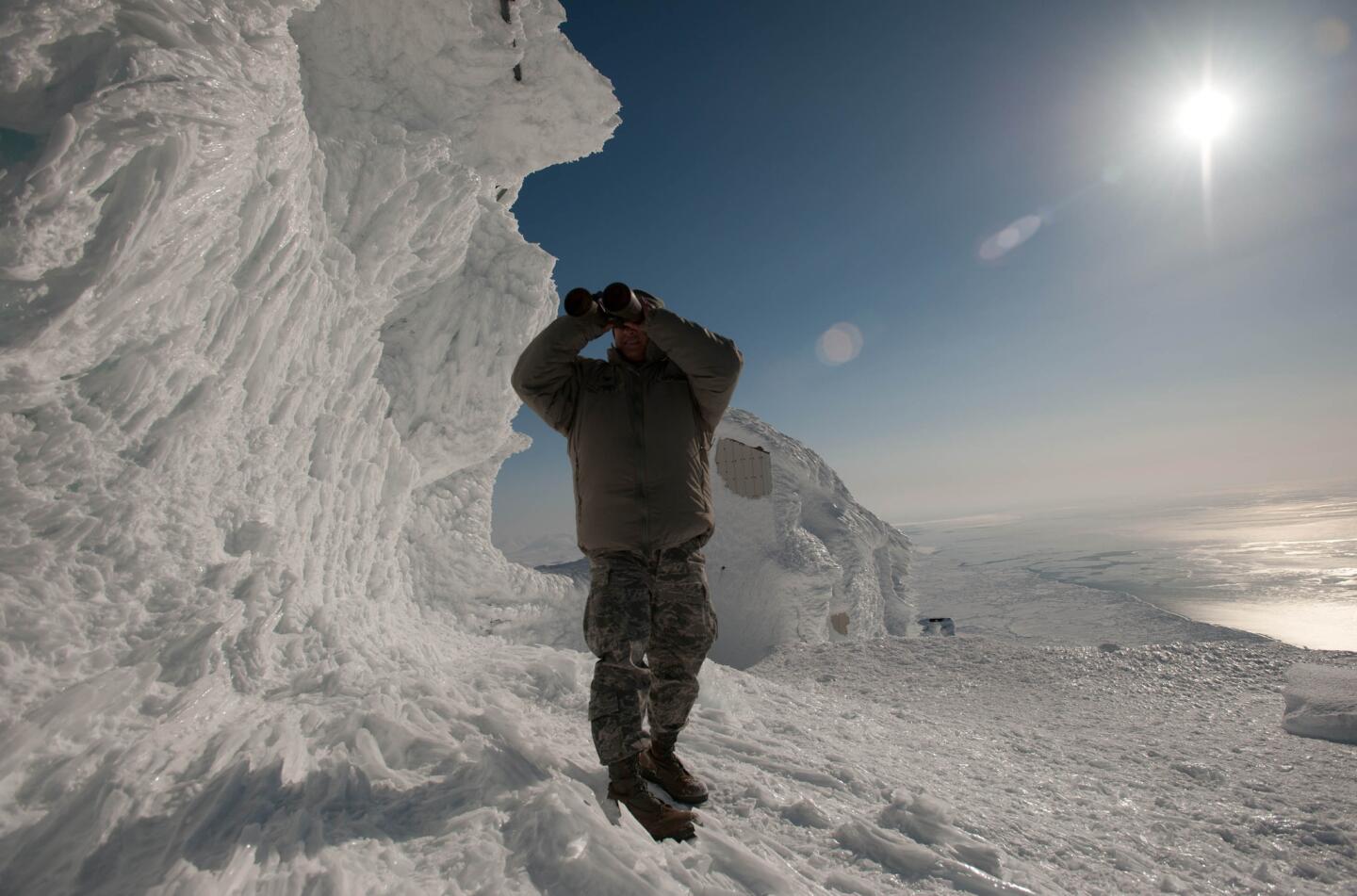 Air Force Col. Frank Flores uses binoculars to look across the Bering Strait toward Siberia from Tin City, a long-range radar station in remote Alaska.