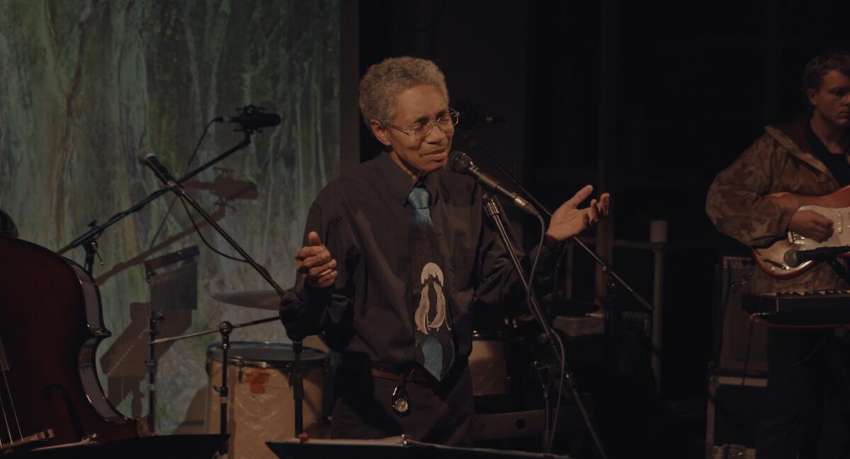 A musician at a microphone holds his hands out in the documentary "Keyboard Fantasies."