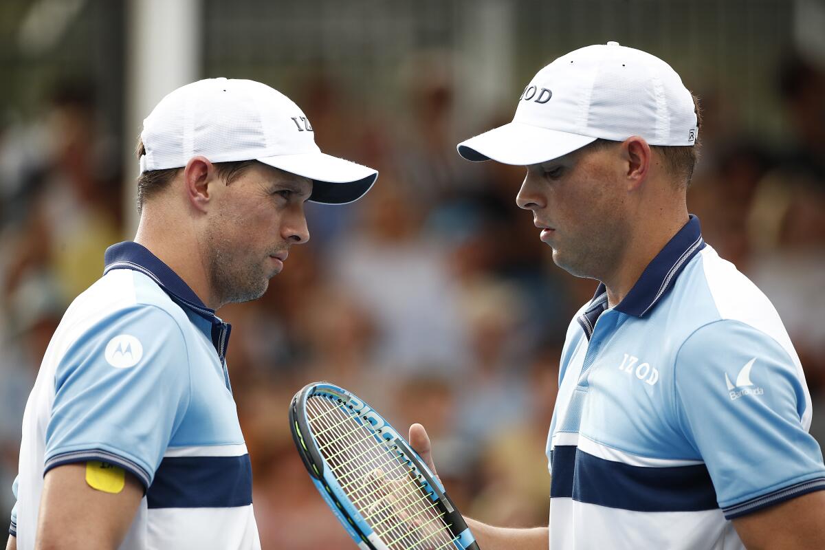 Twins and doubles partners in tennis Mike, left, and Bob Bryan, holding a tennis racket.