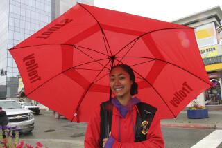 Naomi Reupena-Tuaiao uses an umbrella to protect against intermittent rain Thursday, June 29, 2023, in downtown Anchorage, Alaska, where she stands outside all day for her job in the tourism industry. A year after wildfires in Alaska scorched enough land to cover the state of Connecticut, Alaska in 2023 was off to the slowest start of a wildfire season in three decades thanks to cool and wet conditions. (AP Photo/Mark Thiessen)