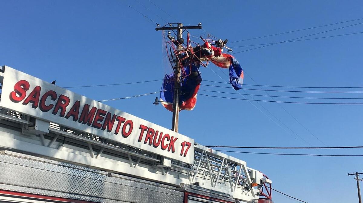 A fire truck below a Santa tangled in power lines