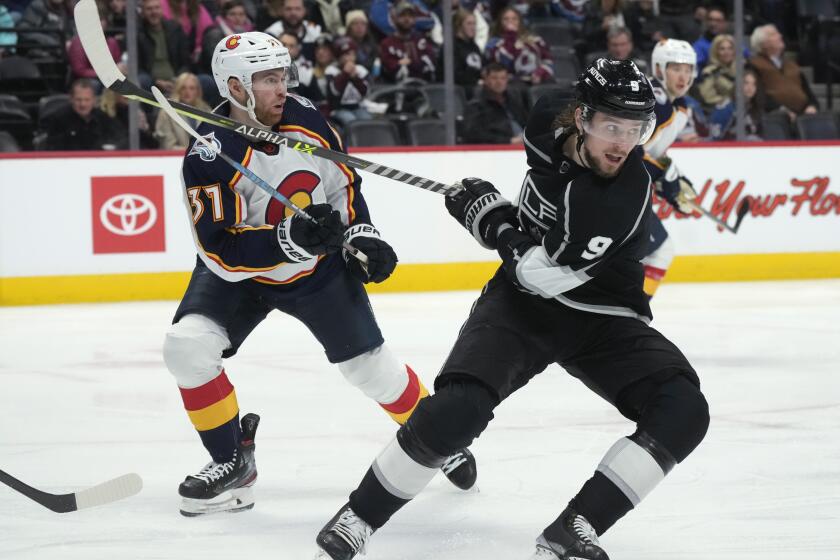 Los Angeles Kings right wing Adrian Kempe, front, gets his stick tangled with that of Colorado Avalanche left wing J.T. Compher during the second period of an NHL hockey game Thursday, Dec. 29, 2022, in Denver. (AP Photo/David Zalubowski)