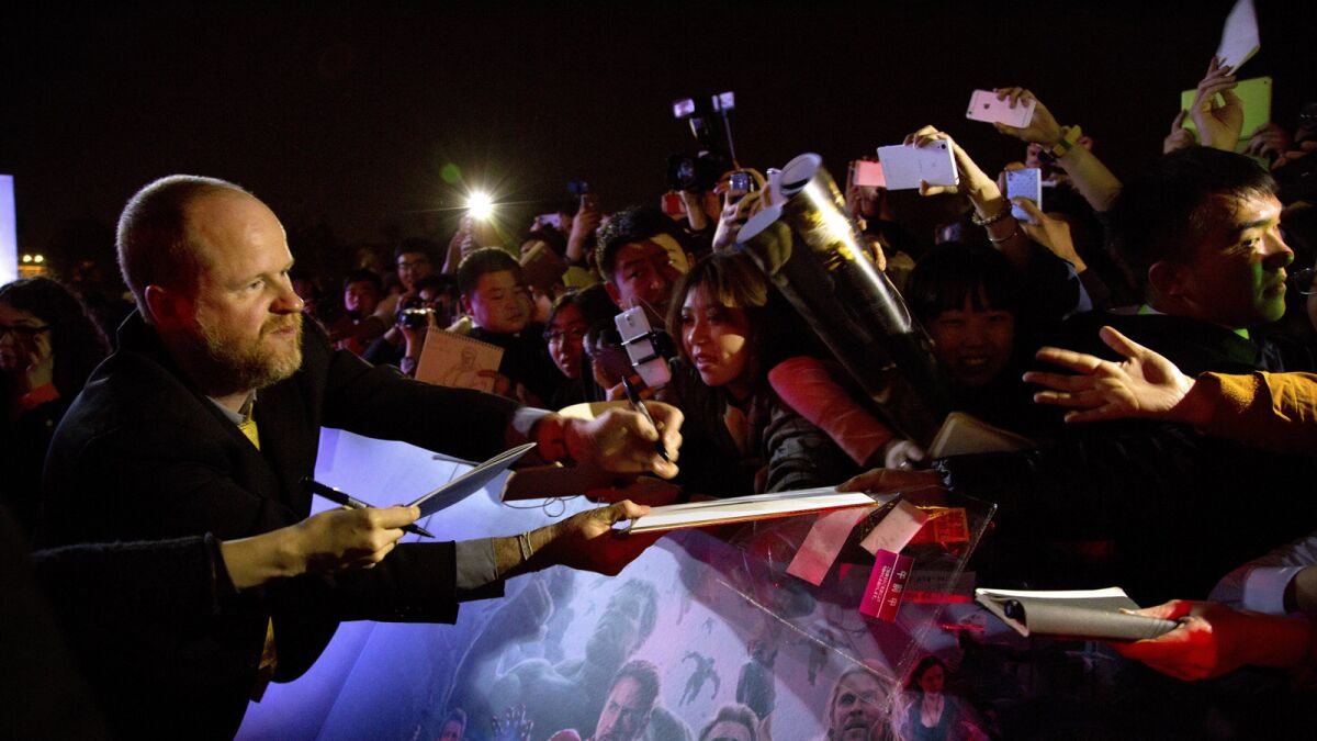 Director Joss Whedon, left, signs autographs for Chinese fans at a red carpet event for his film, Marvel's "Avengers: Age Of Ultron" in Beijing.